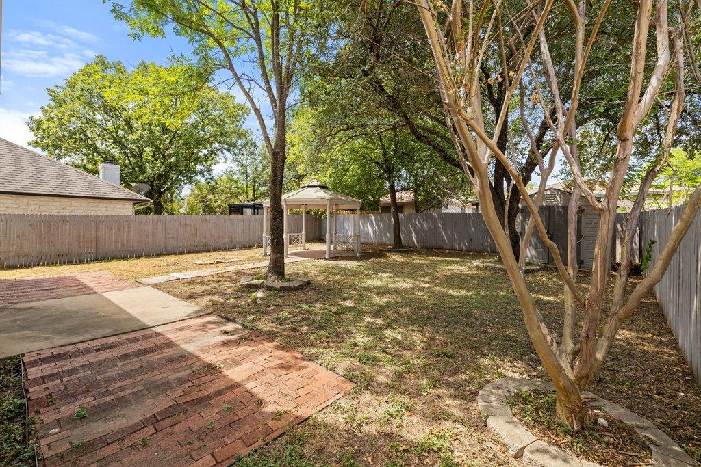 Backyard with mature shade trees, a small gazebo, and a brick patio.