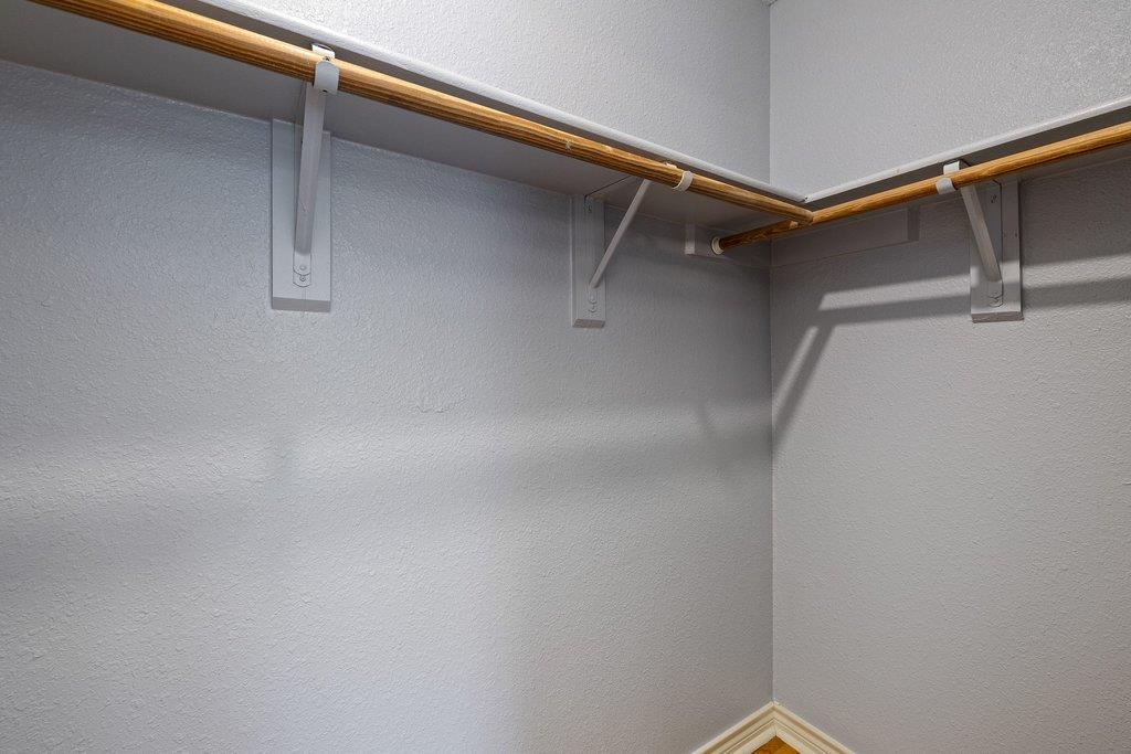 Empty closet with wooden hanging rods and white metal brackets.