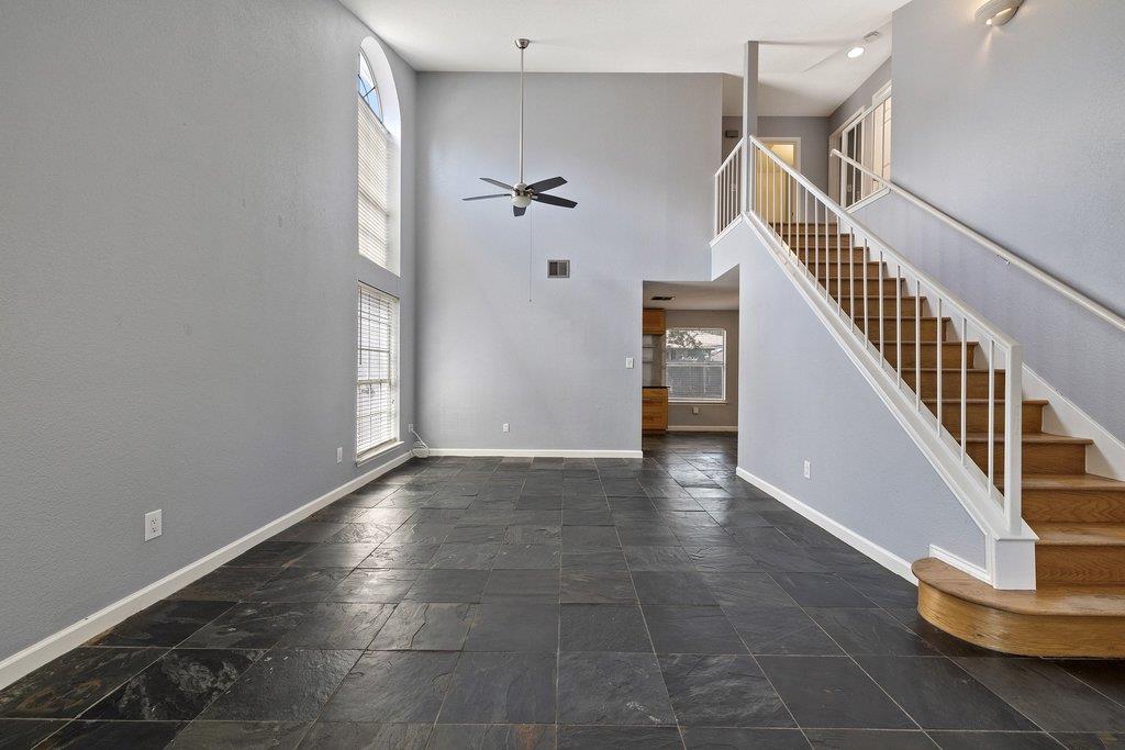 Two-story living area with dark slate tile floors, tall windows, and a wooden staircase.
