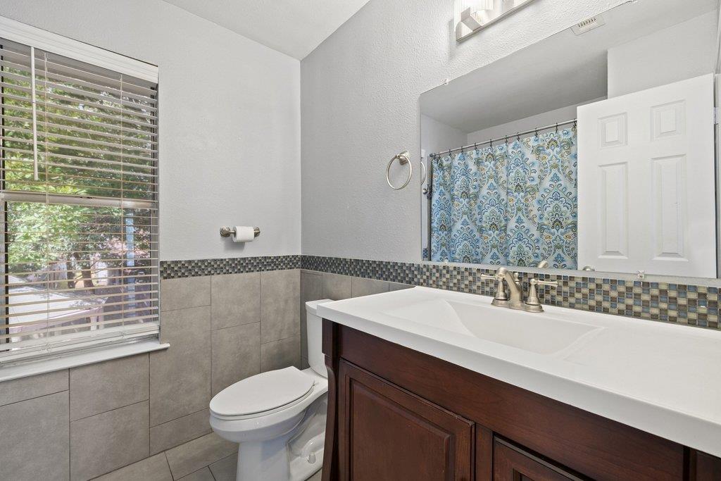 Bathroom with a dark wood vanity, tiled walls, and a window with blinds.