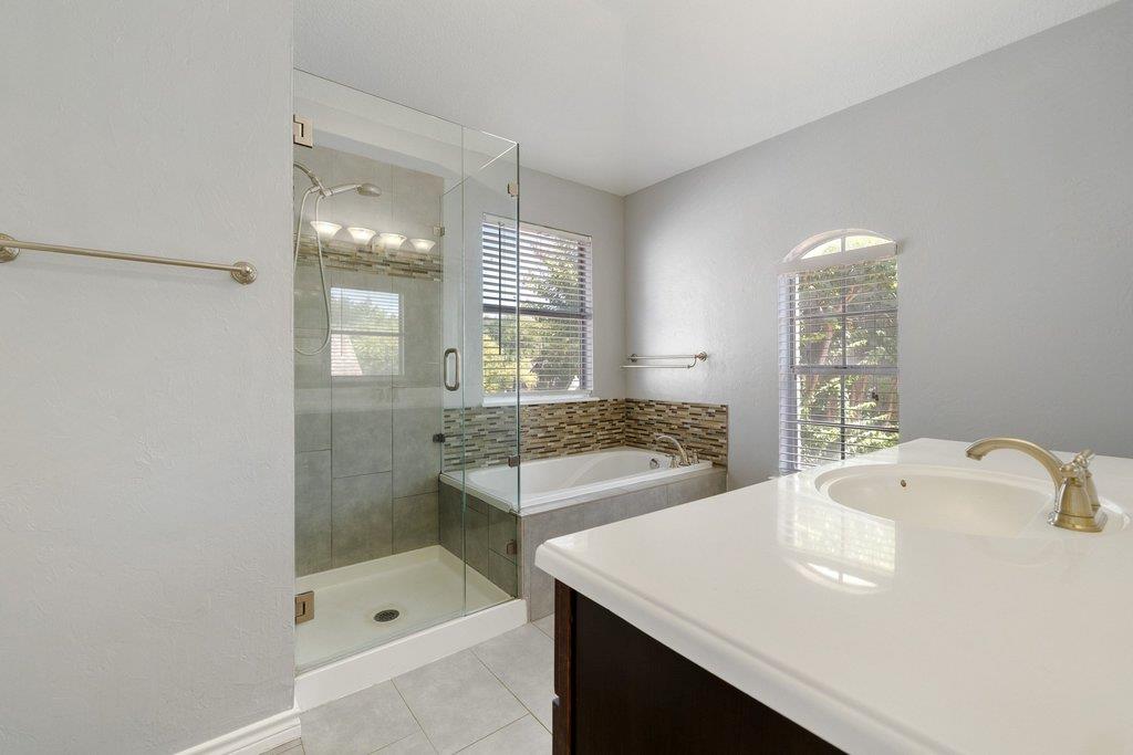 Bathroom with glass shower, soaking tub, and white vanity.