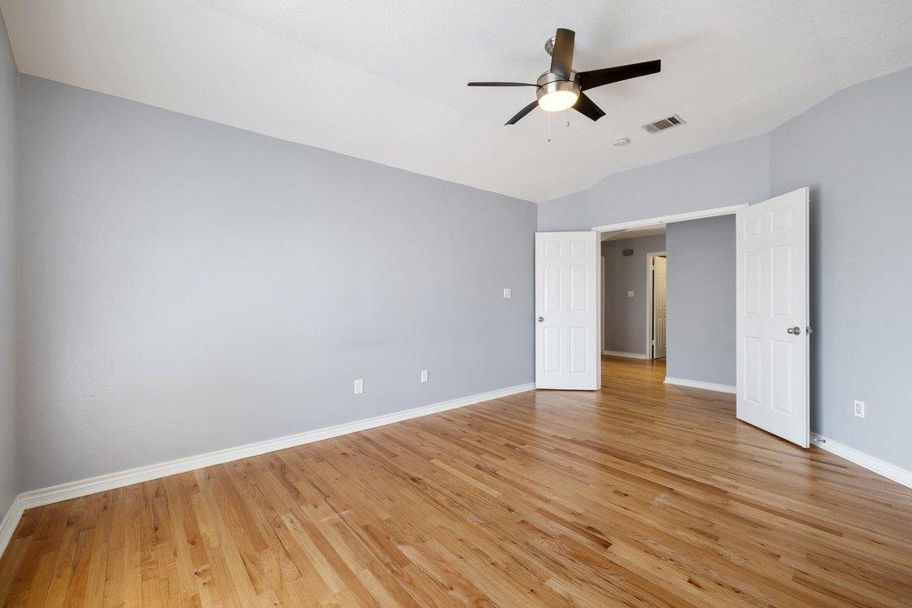 Empty room with hardwood floors, gray walls, and a ceiling fan