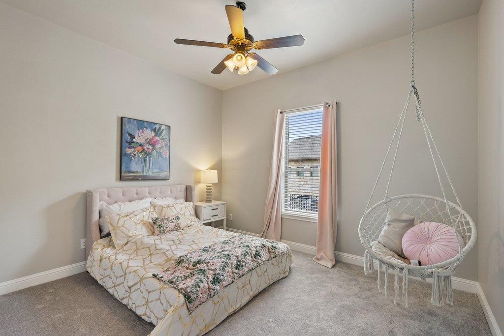 Furnished bedroom with floral bedding and a hanging egg chair beside a curtained window.