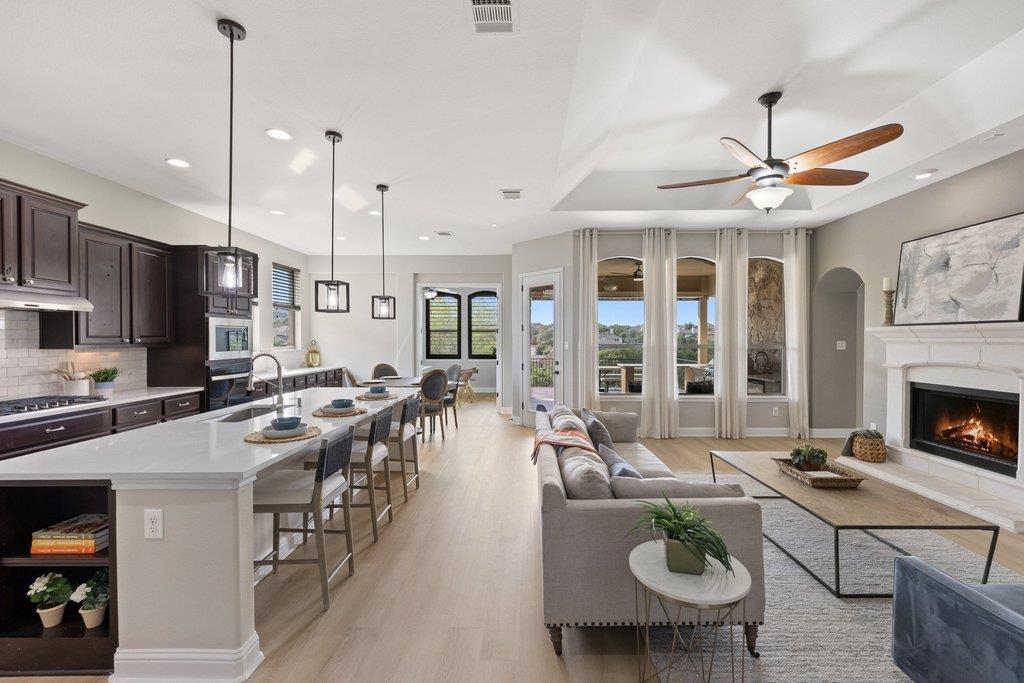 Open-plan kitchen and living room with a large island, fireplace, and tall patio windows.