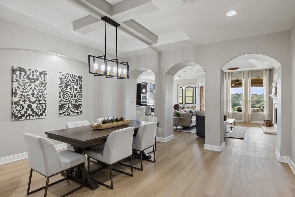 Dining room with a dark wood table, white chairs, and arched openings to the living area.