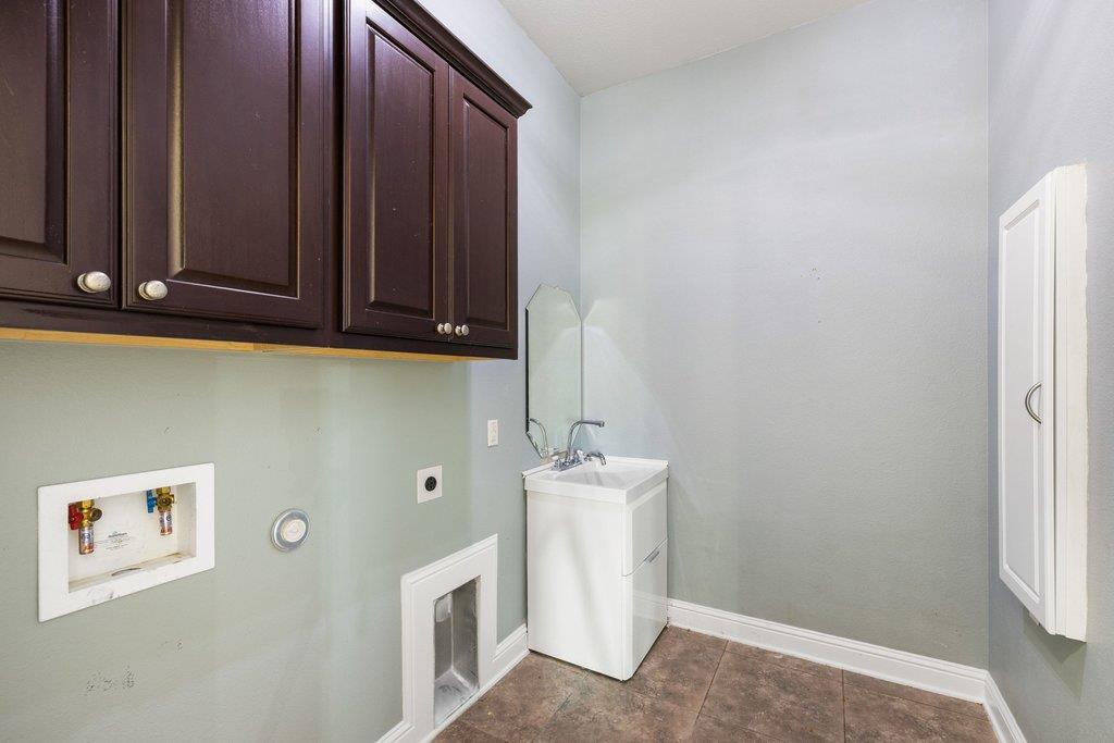 Laundry room with dark wood cabinets, a white washer and a utility sink.