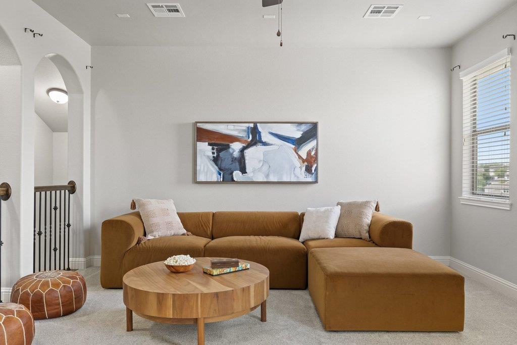 Living room with a brown sectional, round wood coffee table, and abstract wall art.