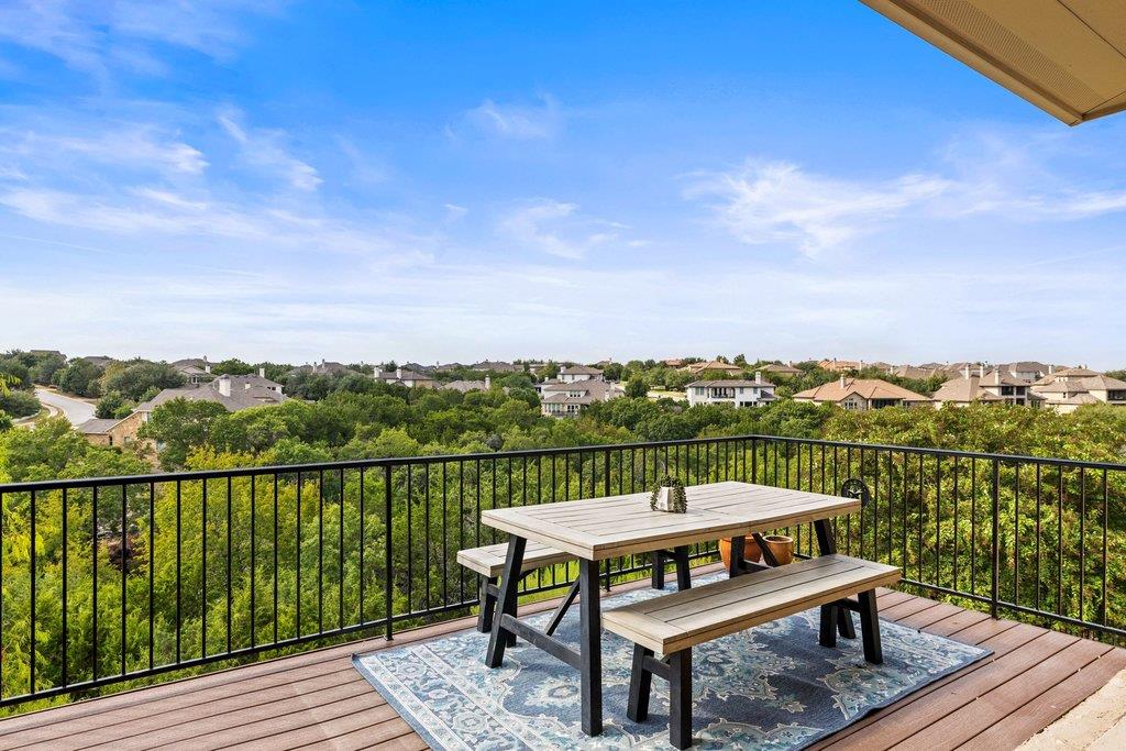 Elevated deck with a picnic table overlooking trees and nearby homes.