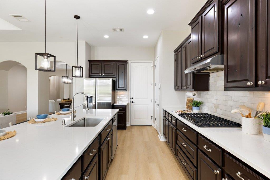 Modern kitchen with dark wood cabinets, white island, stainless steel appliances, and subway tile backsplash.