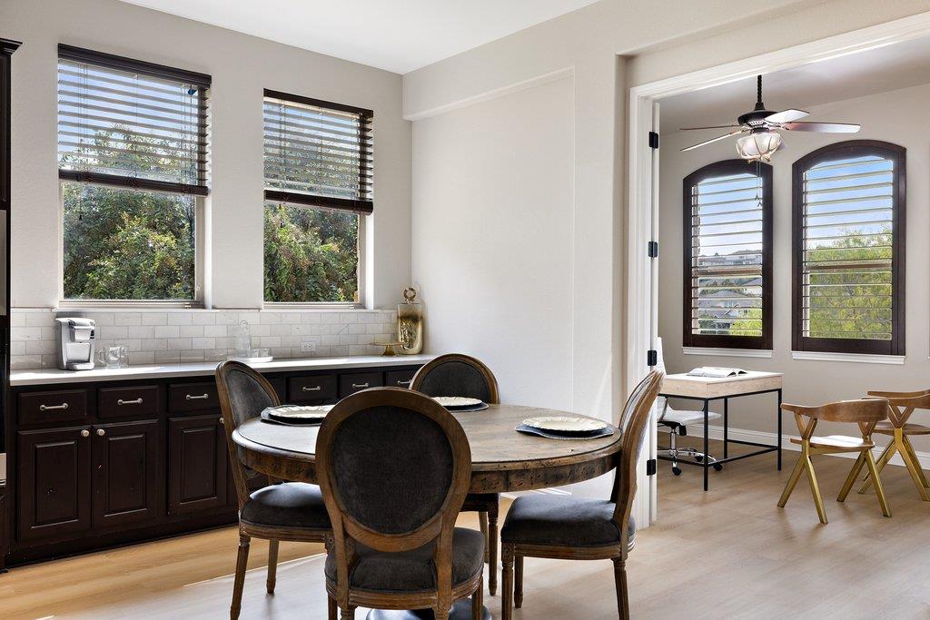 Dining area with a round table, dark built-in cabinets, and windows overlooking greenery.