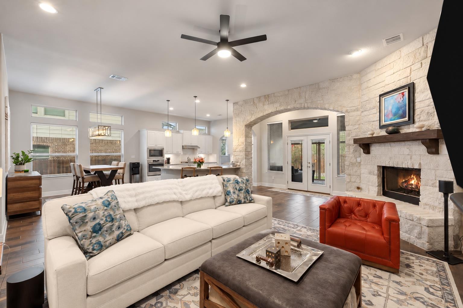 Living room with a stone fireplace, arched stone opening, white sofa, and red leather chair.