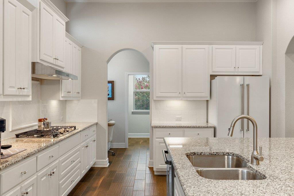 Kitchen with white shaker cabinets, granite counters, gas cooktop, and double-basin sink.