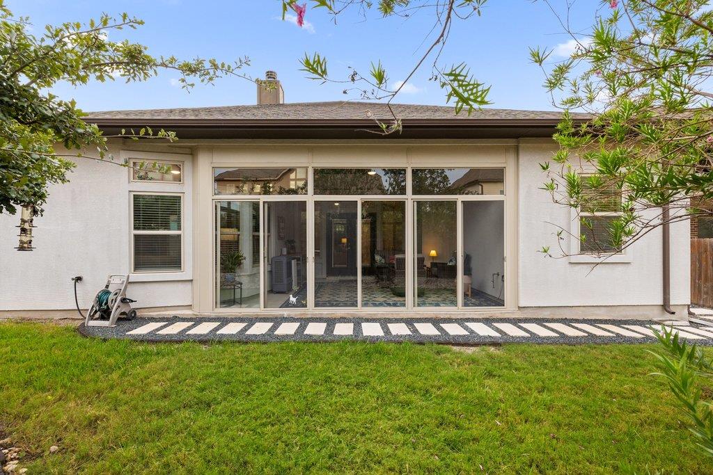 Rear of a white house with broad sliding glass doors, a stone walkway, and lawn.
