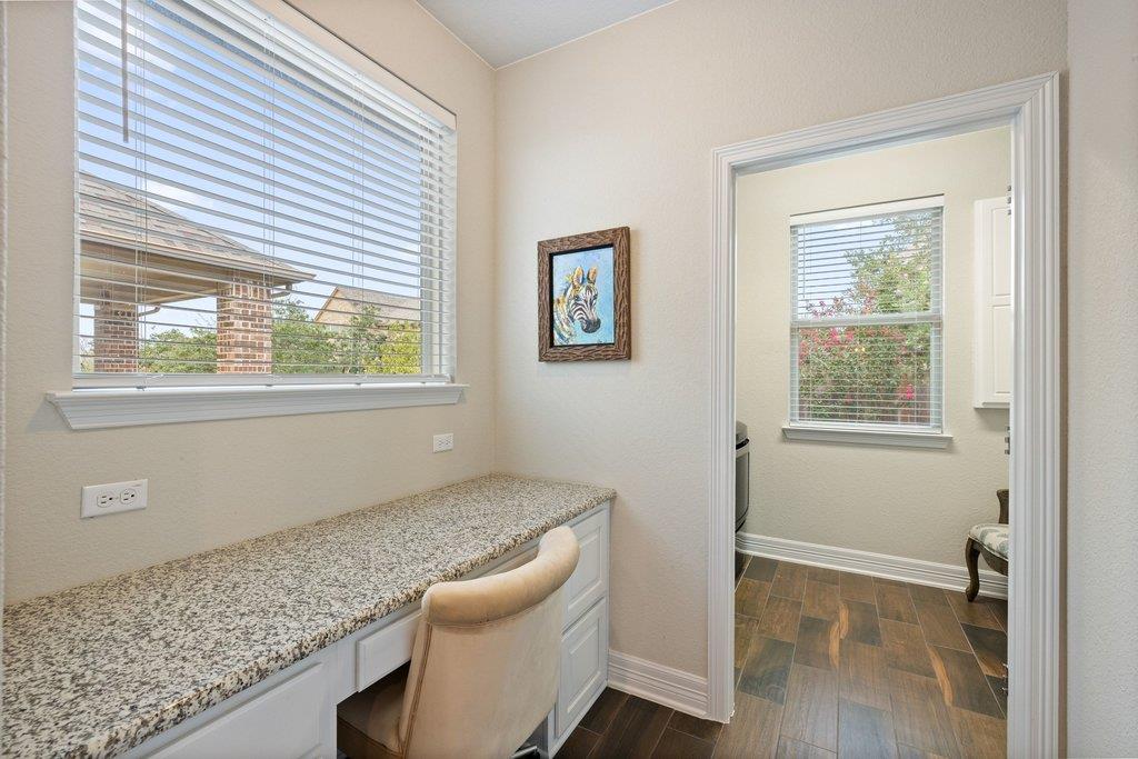 Built-in desk nook with granite countertop and beige chair beside a doorway to an adjoining room.