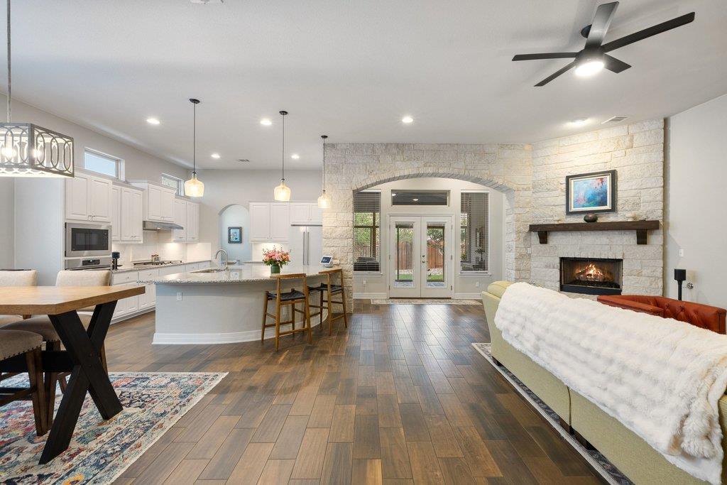 Open-concept living room and kitchen with a stone fireplace and large island.