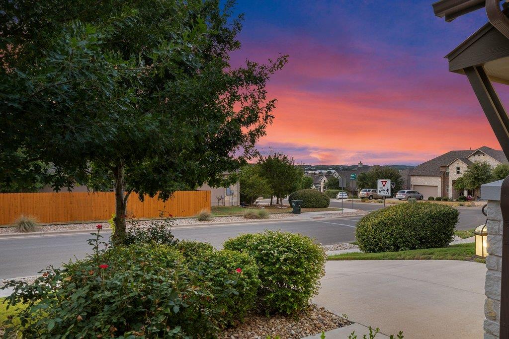 Landscaped driveway and street in front of a home beneath a vivid sunset sky.