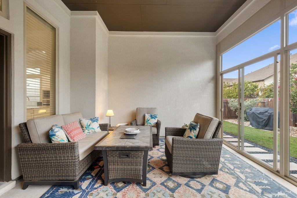 Furnished sunroom with wicker seating and sliding glass doors overlooking a small lawn.