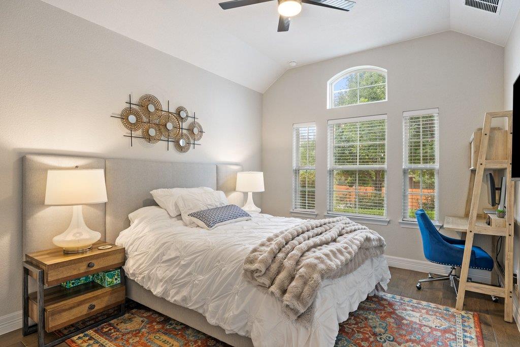 Furnished bedroom with a large white bed, tall shuttered windows, and a vaulted ceiling.