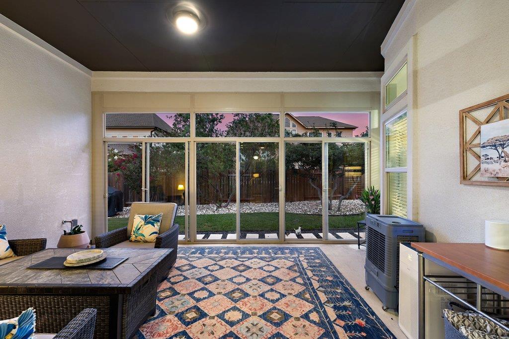 Enclosed sunroom with wicker seating and sliding glass doors overlooking a fenced backyard.