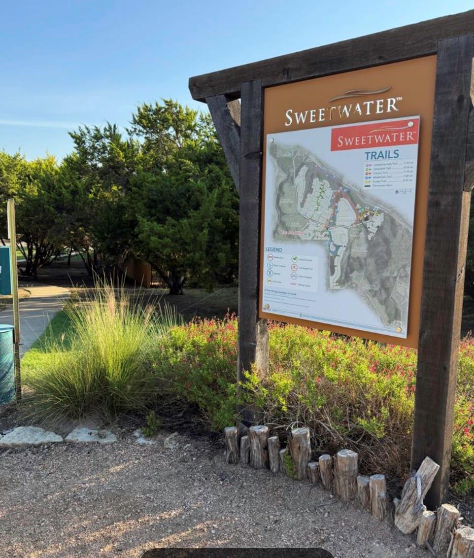 Sweetwater Trails map sign beside a landscaped path and trees.