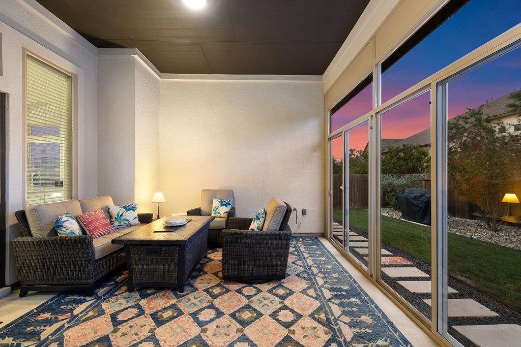 Furnished sunroom with wicker seating, a patterned rug, and sliding glass doors overlooking the garden.