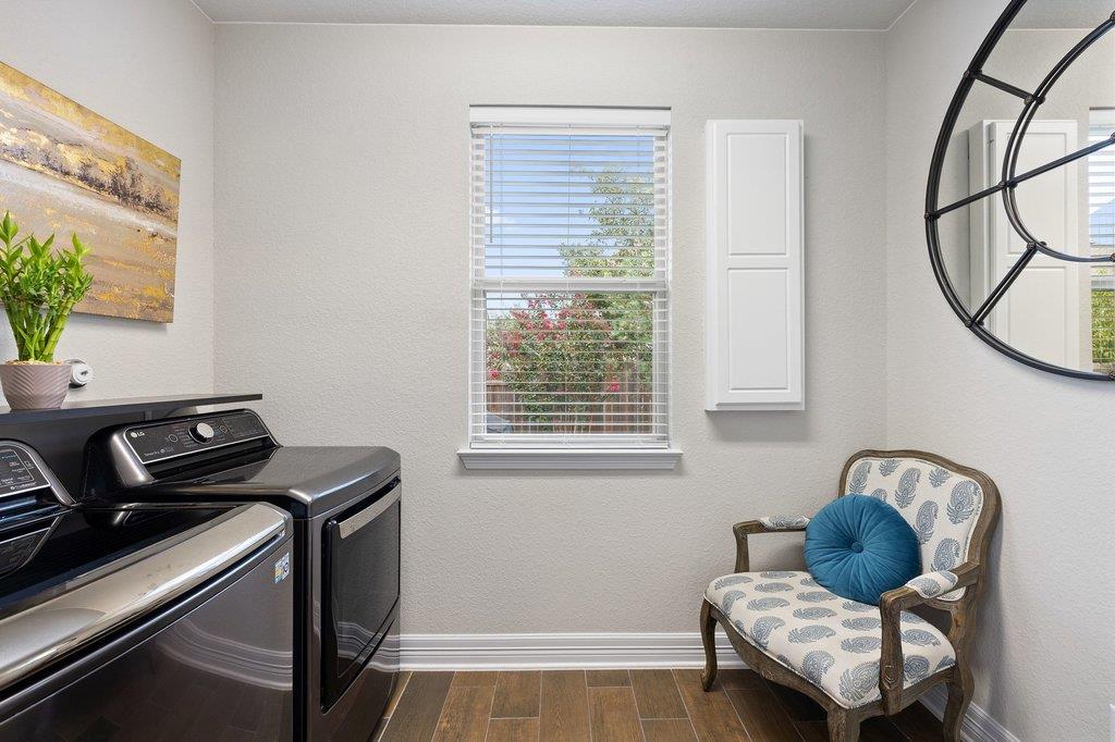 Laundry room with black washer and dryer, window blinds, and a patterned armchair.