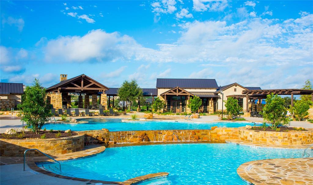 Community pool with a stone waterfall edge, lounge seating, and a timber-trimmed clubhouse.