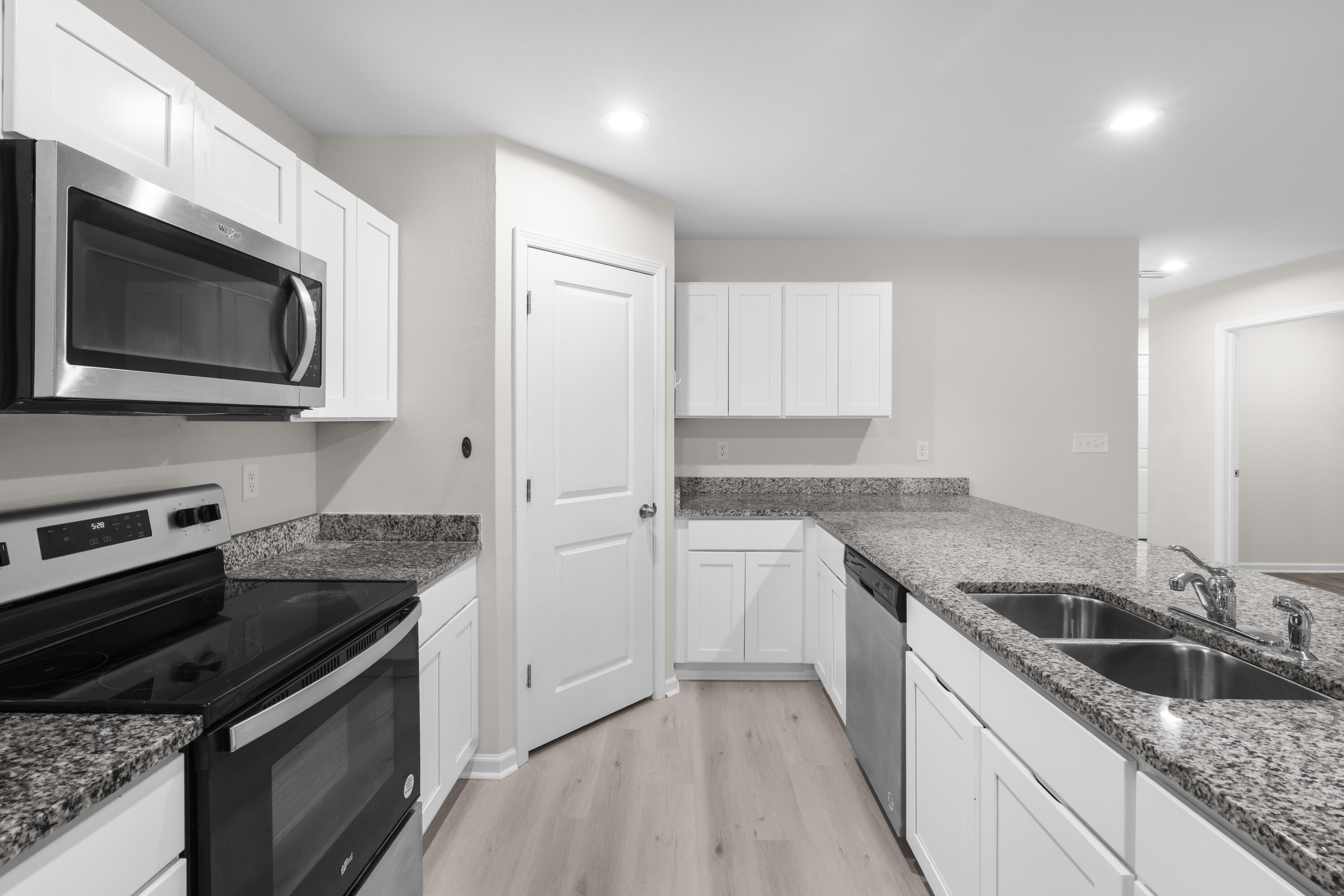 Kitchen with white cabinets, granite counters, stainless appliances, and a double-basin sink.