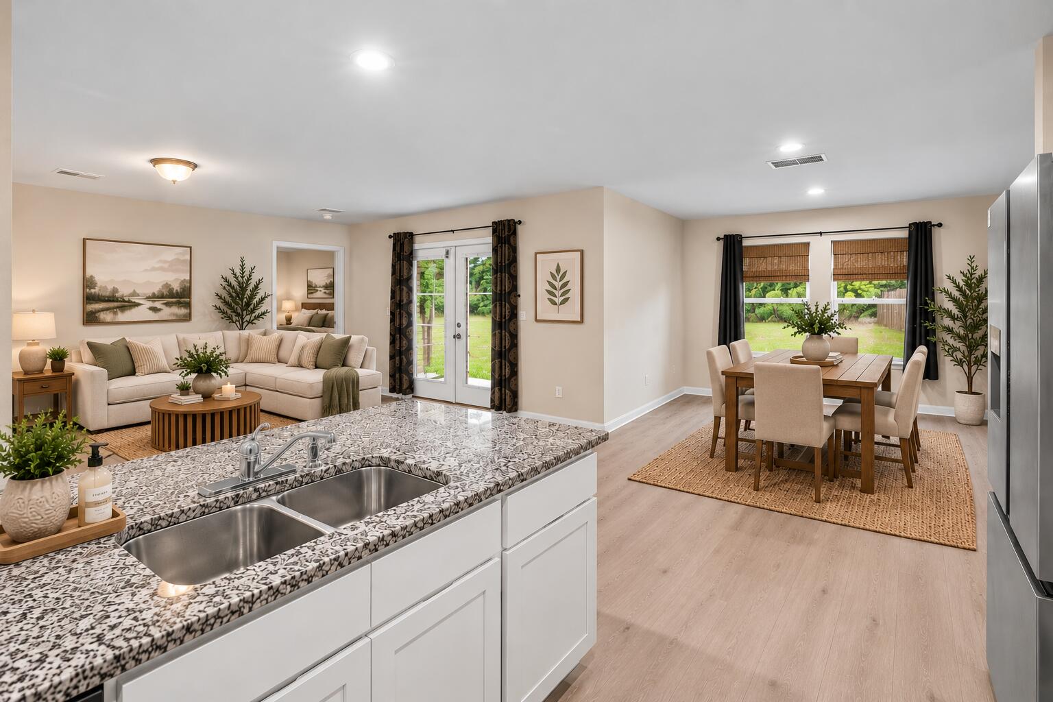 Open-plan kitchen, dining area, and living room with a stone island and French doors to the yard.