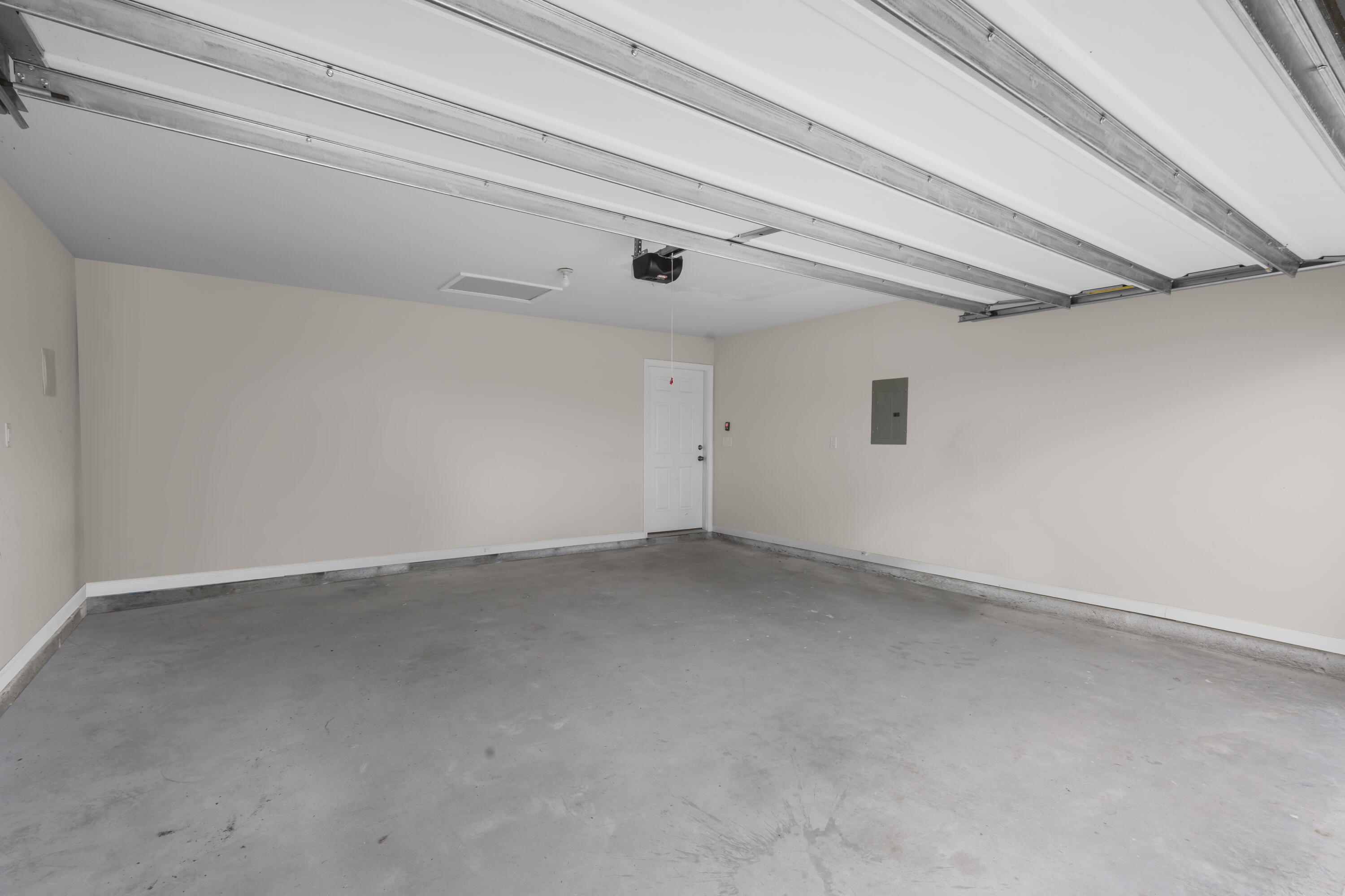 Empty garage with a concrete floor and open overhead door.