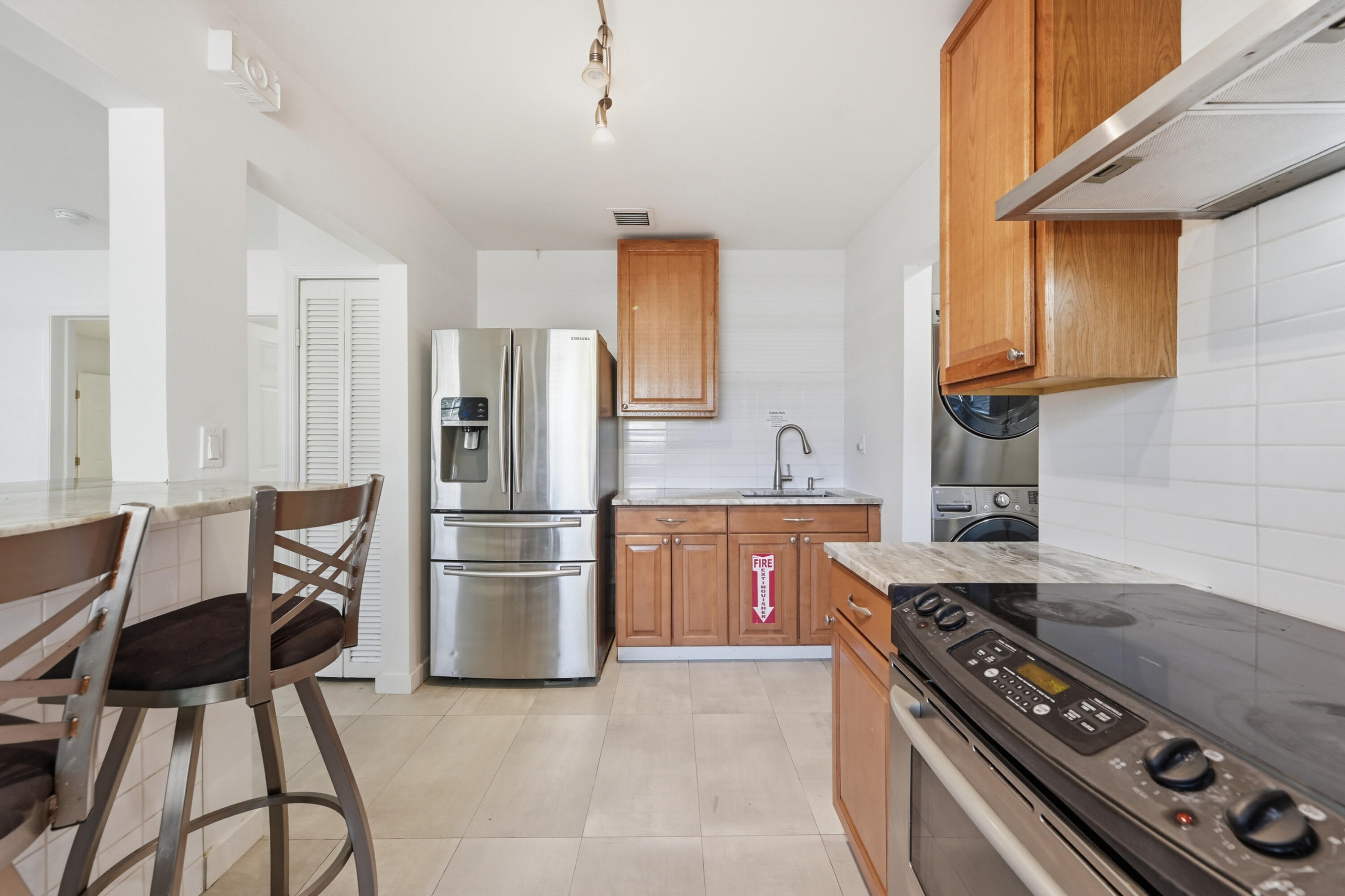 Kitchen with wood cabinetry, stainless steel appliances, and a breakfast bar with stools.
