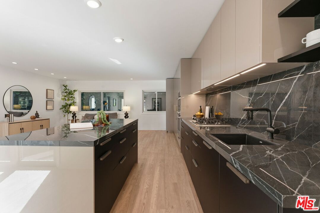 Modern kitchen with a dark marble island and dramatic veined stone backsplash.
