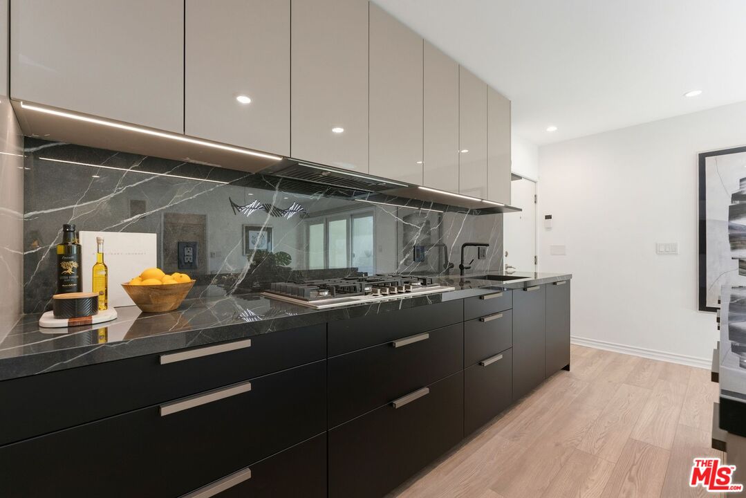 Modern kitchen with black cabinetry, dramatic veined stone counters, and a gas cooktop.