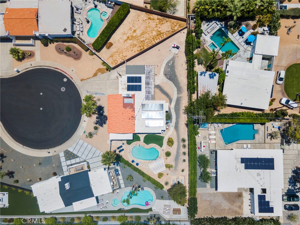 Aerial view of a Palm Springs home with a kidney-shaped pool and rooftop solar panels.