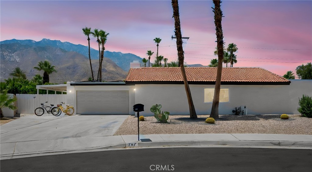 Single-story home with a tiled roof, desert landscaping, and mountain backdrop at dusk.