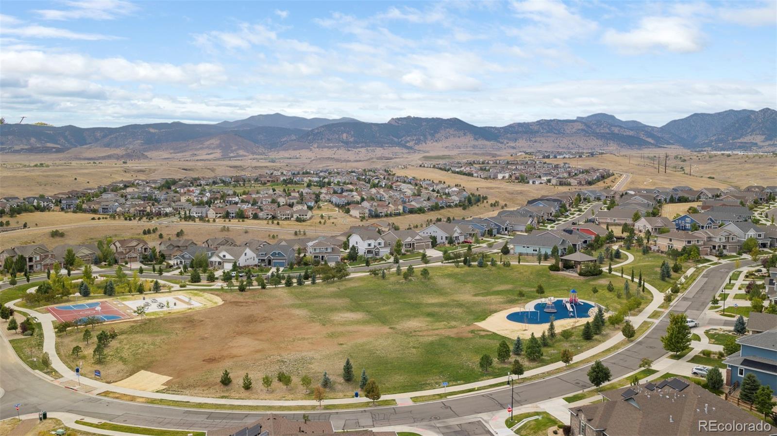Aerial view of a residential neighborhood and parks, with mountains across the horizon.