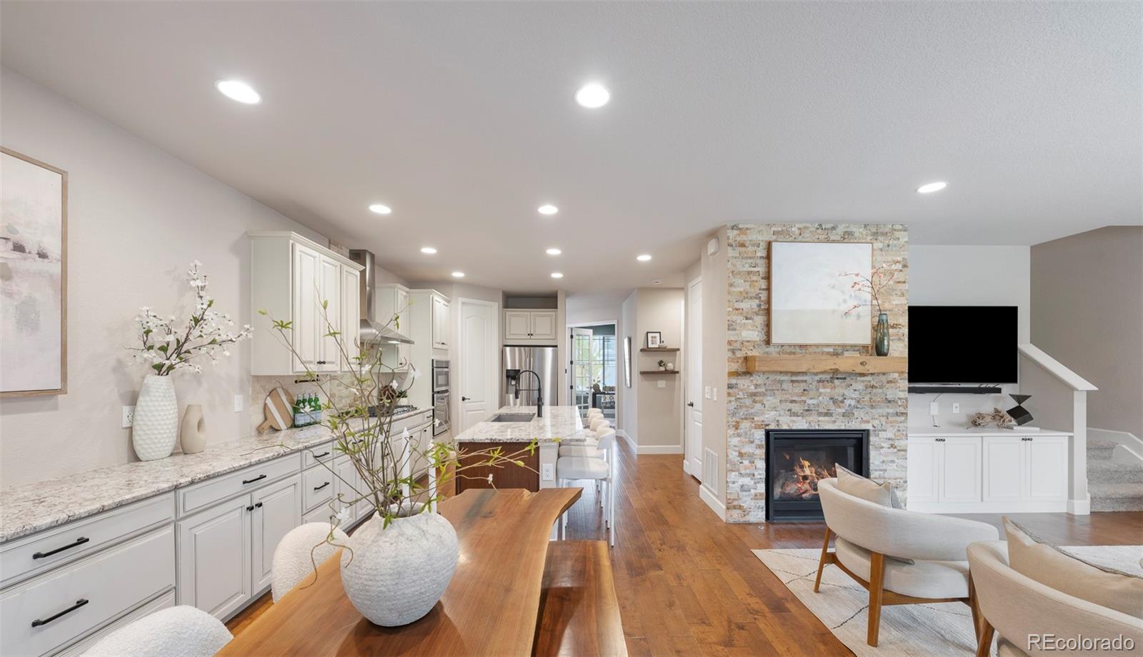 Open-plan kitchen and living area with a wood island and stone fireplace.