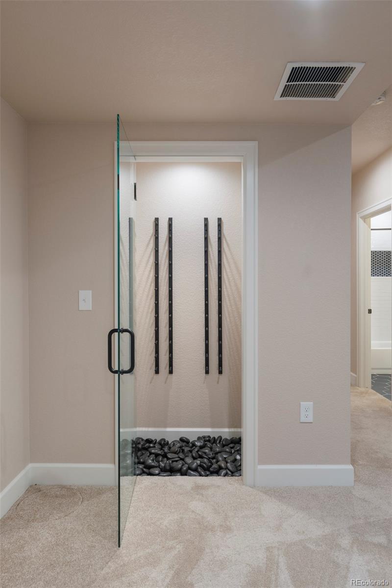 Glass-enclosed shower with a dark pebble floor and vertical wall fixtures.