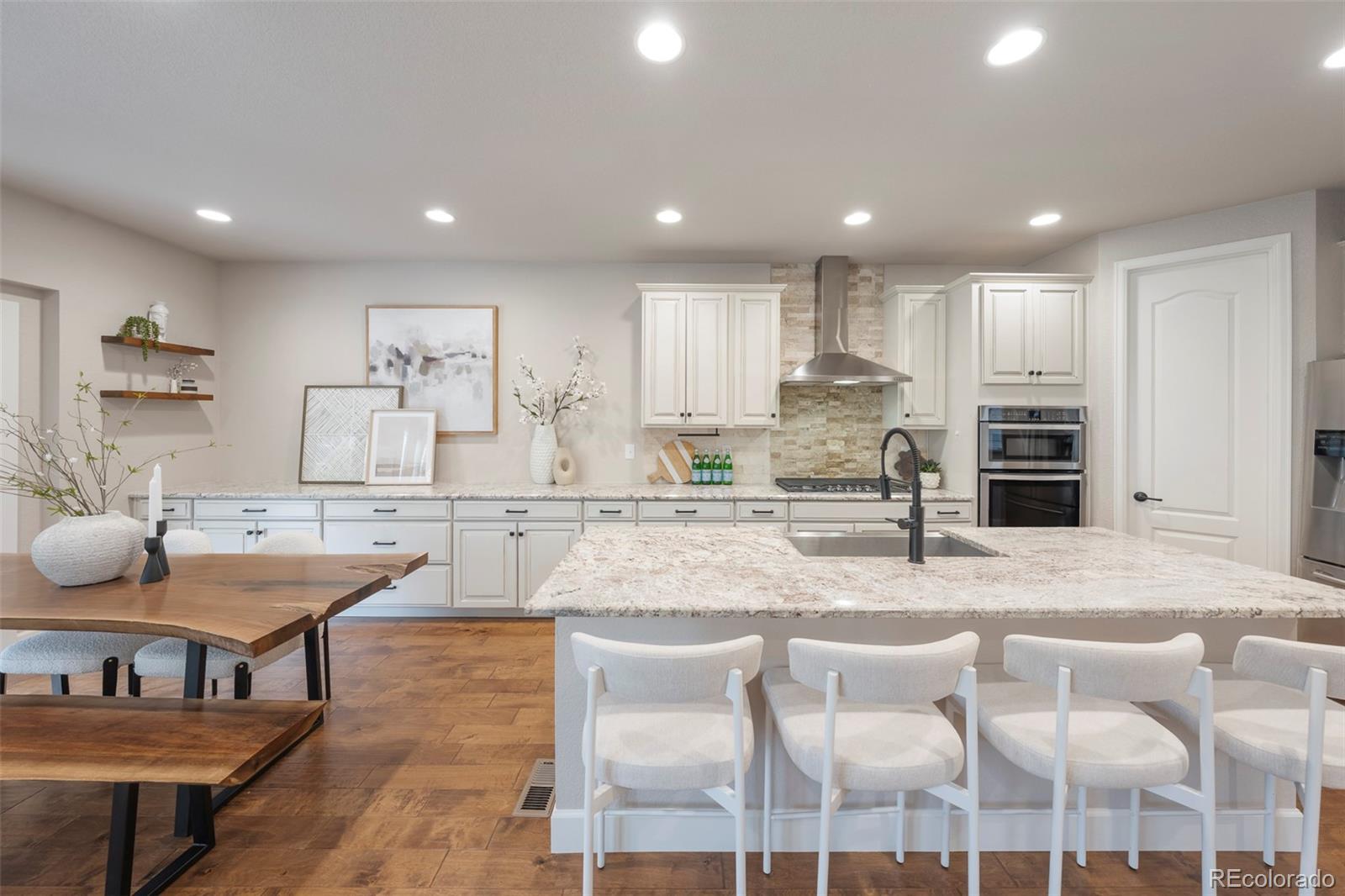 Open-plan kitchen with a large stone island, white cabinets, and stainless steel appliances.