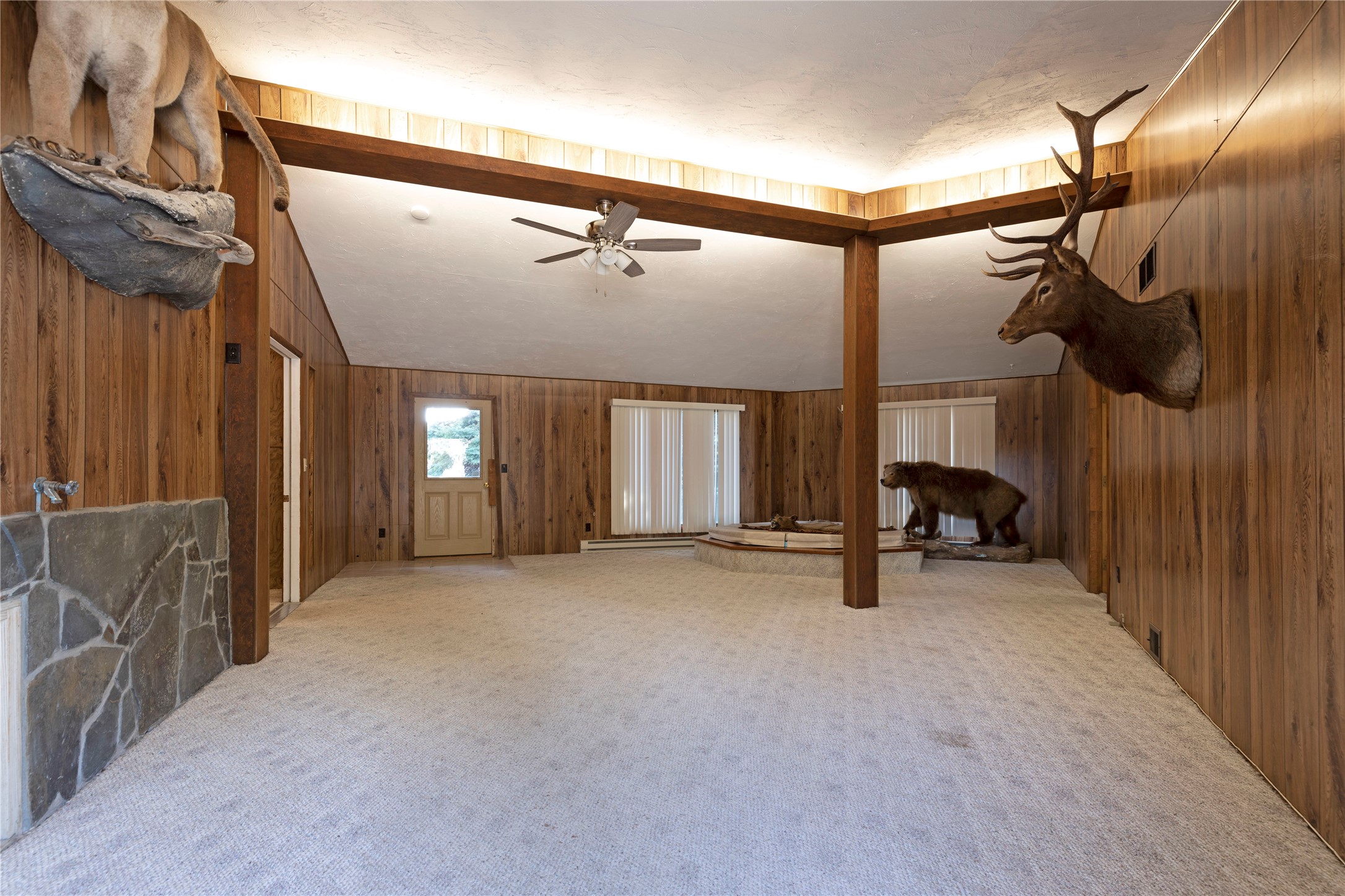 Wood-paneled living room with exposed beams and mounted elk and bear taxidermy.