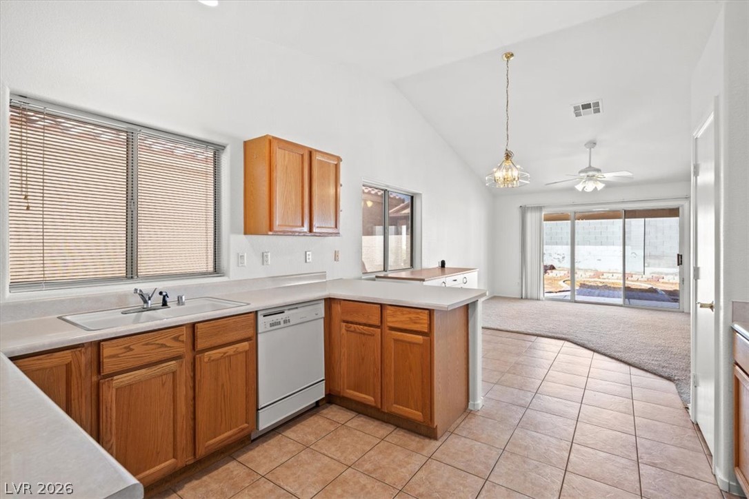 Kitchen with warm wood cabinets and peninsula opening to a carpeted living area with sliding glass doors.