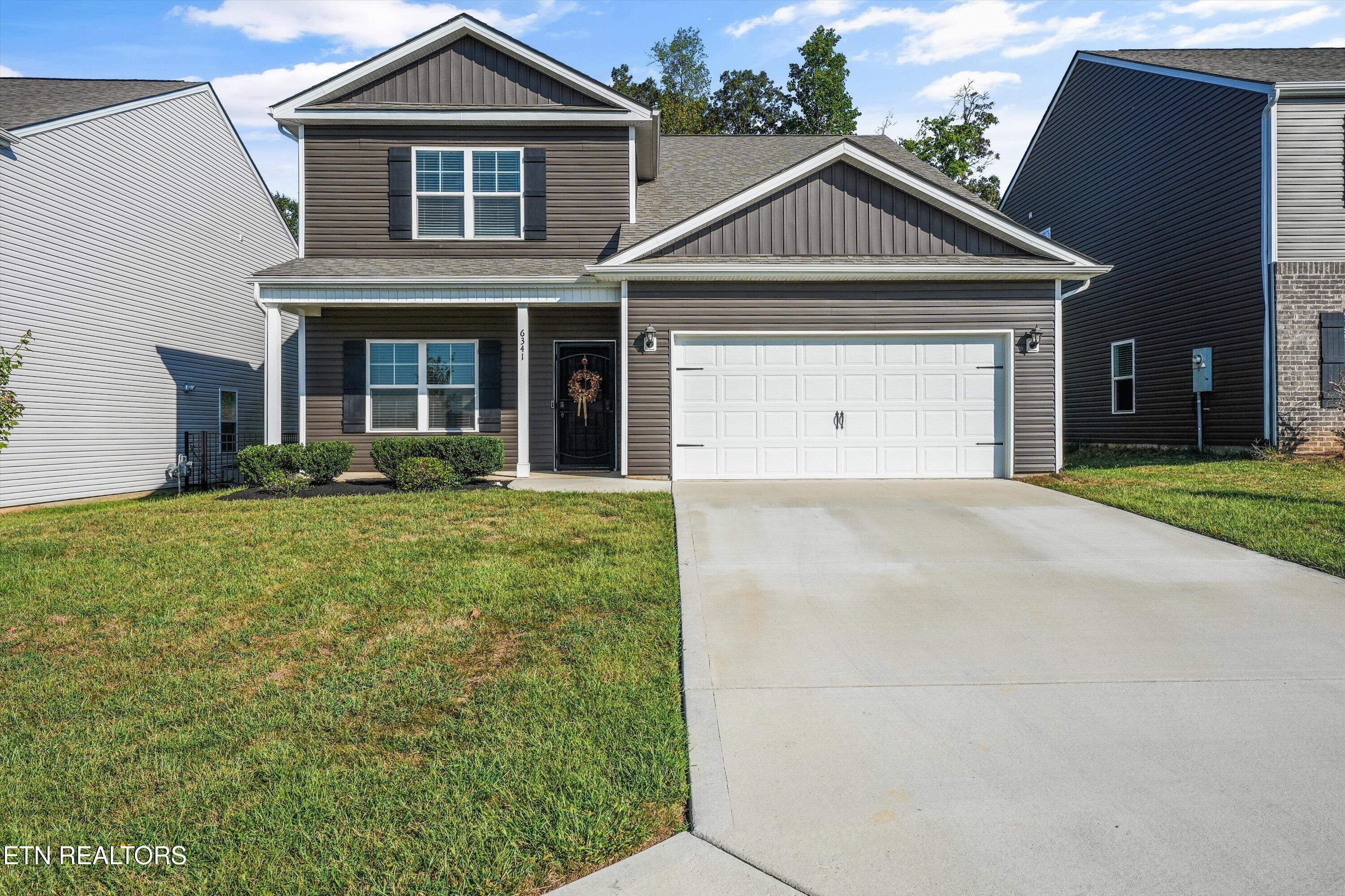 Two-story gray house with a double garage, front lawn, and wide concrete driveway.