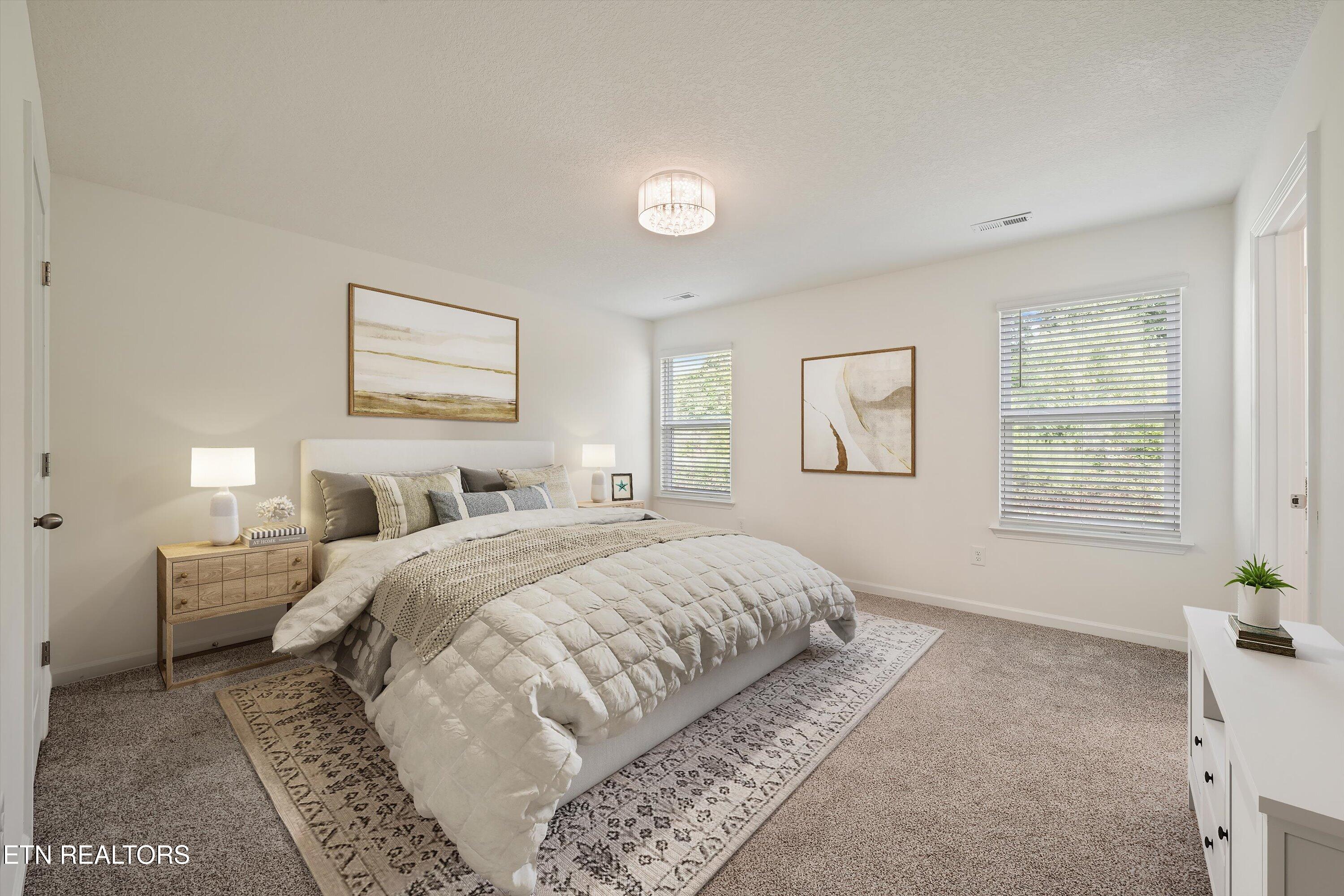 Staged bedroom with a white bed, patterned rug, abstract art, and windows with blinds.