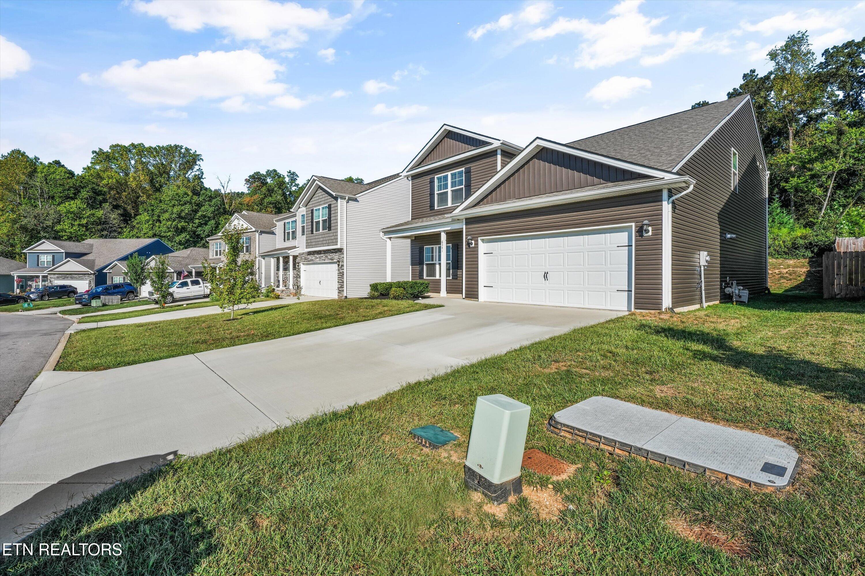 Two-story brown-sided home with a white double garage and broad concrete driveway.