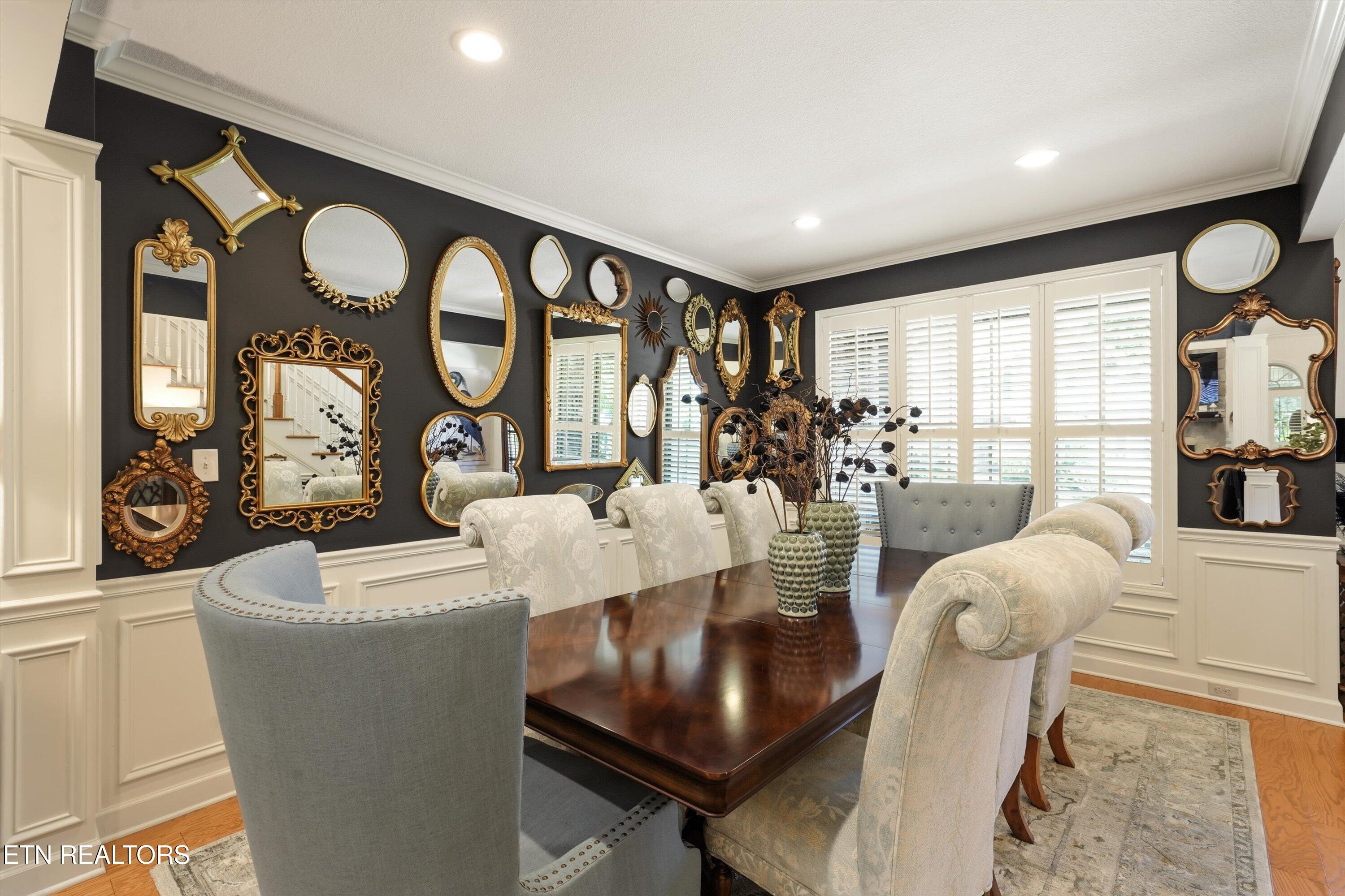 Dining room with a dark wood table, upholstered chairs, and a wall covered in ornate mirrors.