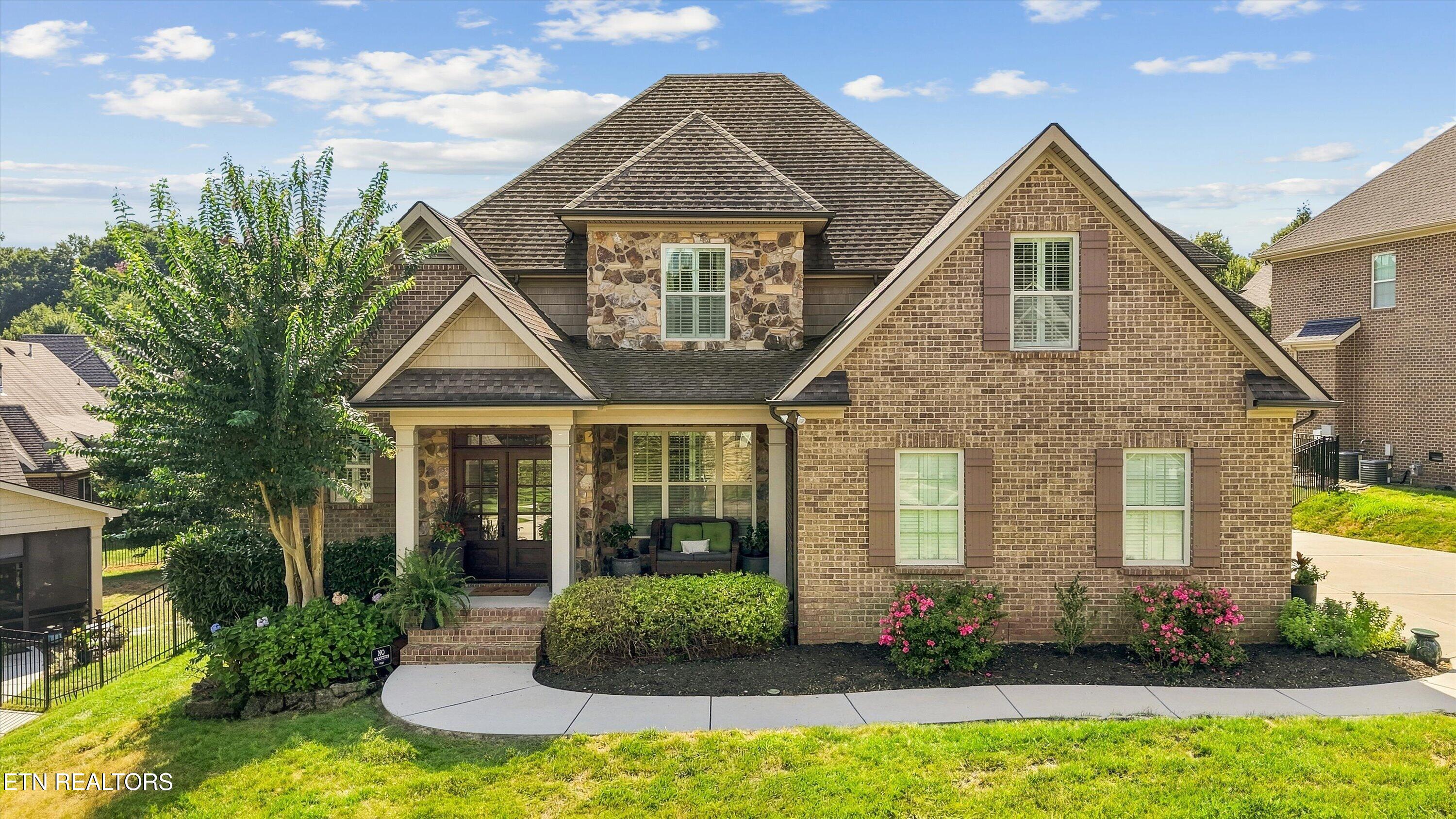 Brick-and-stone home with gabled rooflines, covered entry, and landscaped front garden.