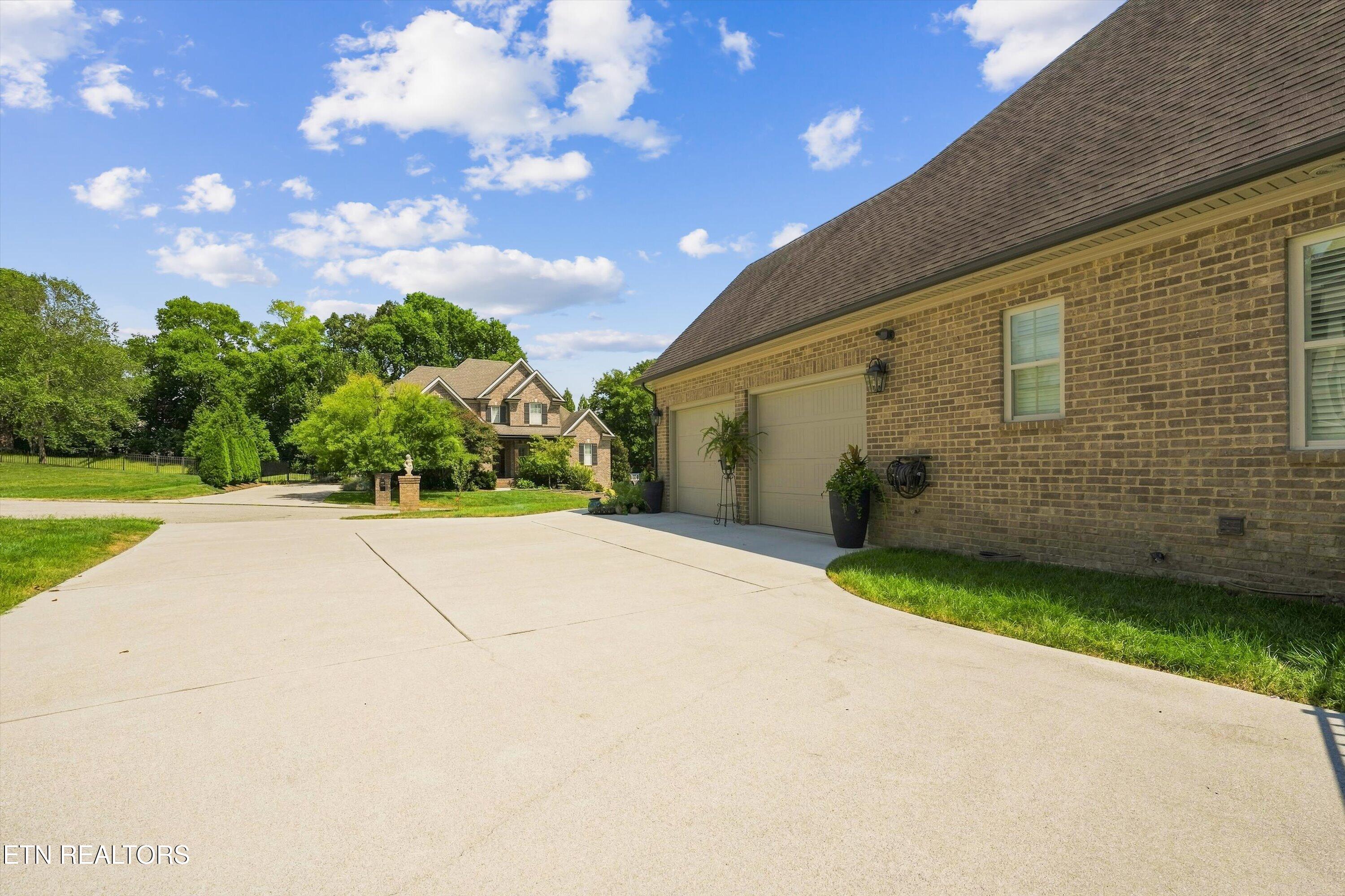 Brick home with a wide concrete driveway, two garage doors, and a neighboring house in the background.