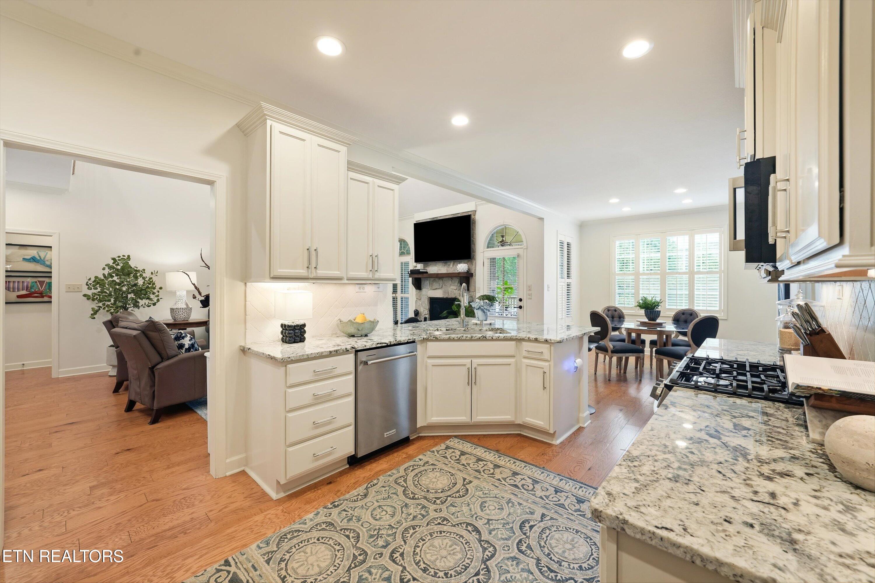 Bright kitchen with granite island, white cabinets, gas range, and adjoining dining area.