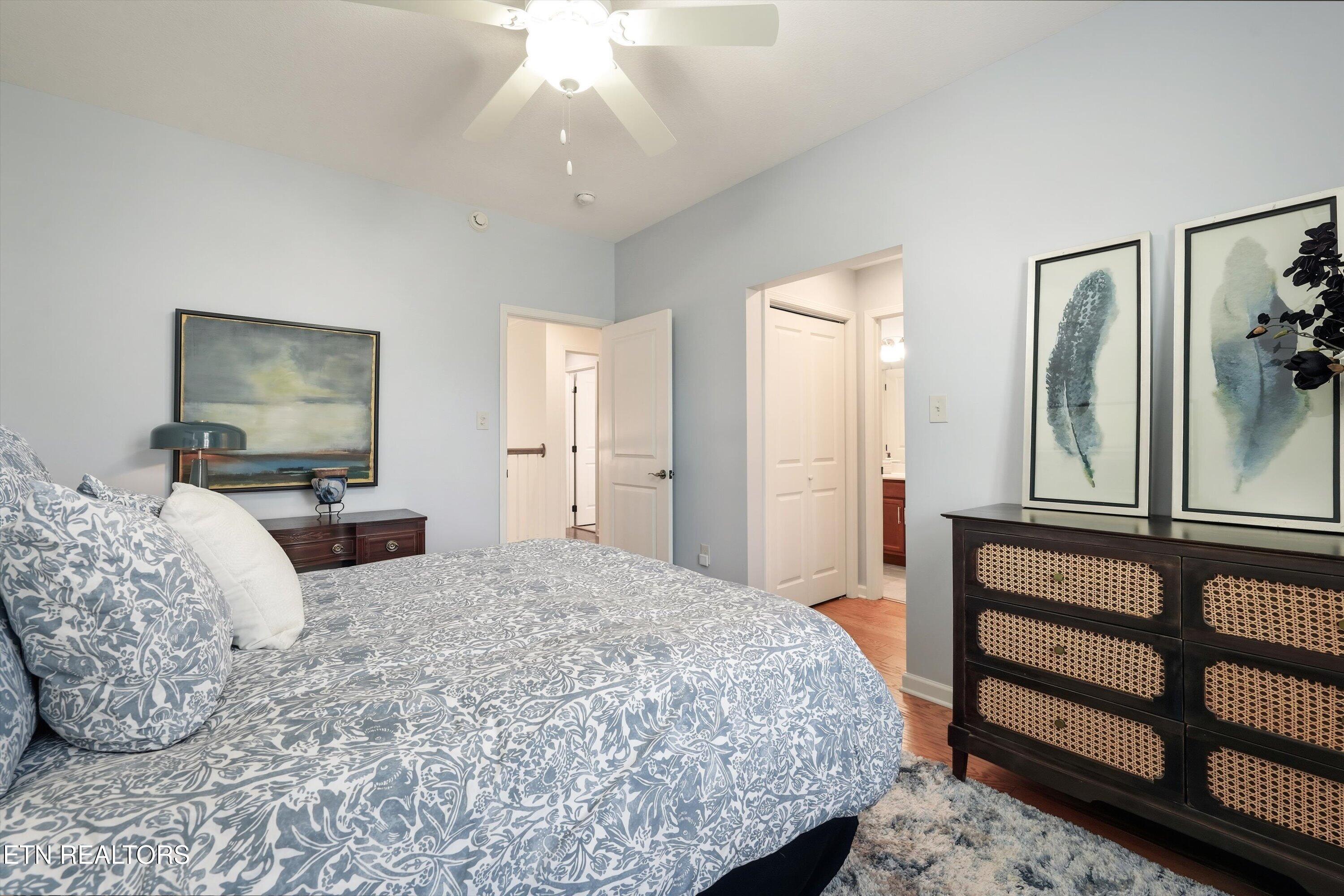 Furnished bedroom with blue-and-white patterned bedding and a dark cane-front dresser.
