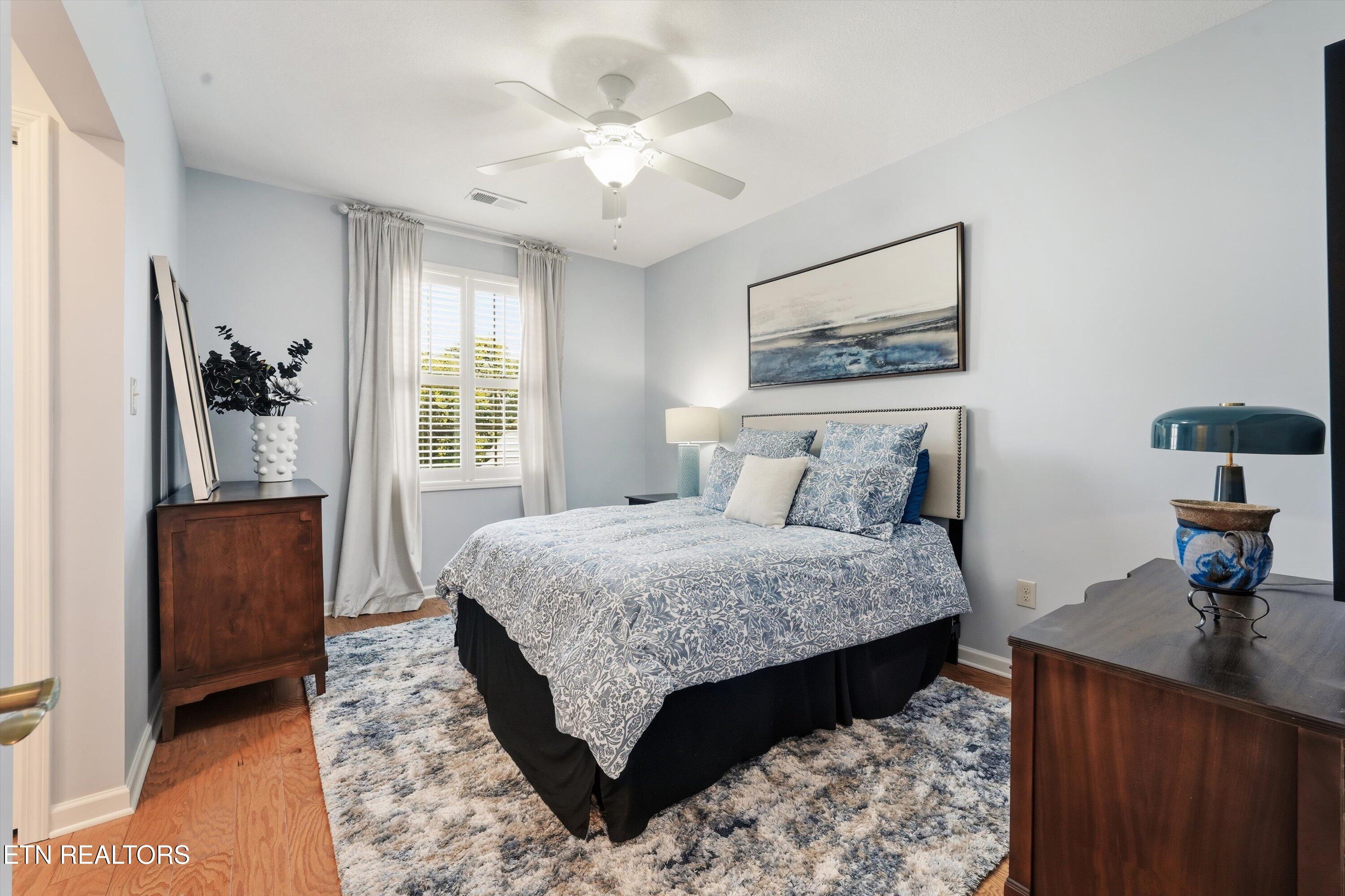 Bedroom with blue-and-white patterned bedding, shuttered windows, and dark wood dressers.
